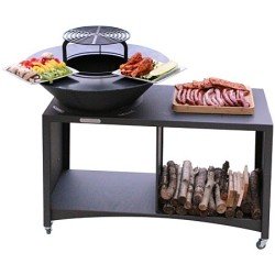 Brasero sur table basse avec bois de chauffage et plats prêts à cuisiner à côté, prêt pour un barbecue extérieur.